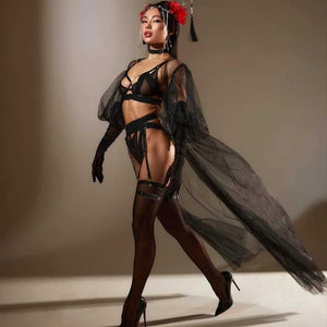 Lingerie Geisha en tulle noir avec découpes franches et bandes élastiques. Culotte ouverte, porte-jarretelles, soutien-gorge et choker assortis. Détails métalliques et ajustements précis. Ligne graphique signée Pivovarova. Fabriqué à la main en Ukraine.