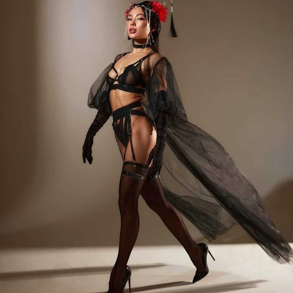 Lingerie Geisha en tulle noir avec découpes franches et bandes élastiques. Culotte ouverte, porte-jarretelles, soutien-gorge et choker assortis. Détails métalliques et ajustements précis. Ligne graphique signée Pivovarova. Fabriqué à la main en Ukraine.