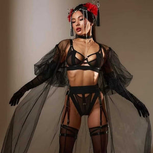 Lingerie Geisha en tulle noir avec découpes franches et bandes élastiques. Culotte ouverte, porte-jarretelles, soutien-gorge et choker assortis. Détails métalliques et ajustements précis. Ligne graphique signée Pivovarova. Fabriqué à la main en Ukraine.