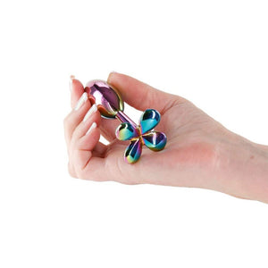 Plug anal en acier inoxydable finition irisée, motif fleur à la base, présenté sur fond clair, sélection Brigade Mondaine Paris.