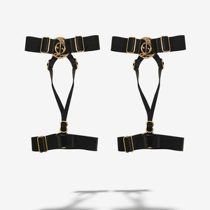 Harnais pour chevilles ajustables accessoire de lingerie réalisé en élastiques haut de gamme recyclés, doux mais résistants, ornés de composants en Zamac plaqué or 18 carats anti-rayures, lavables et hypoallergéniques ainsi que de l’anneau signature QRUCIFIX