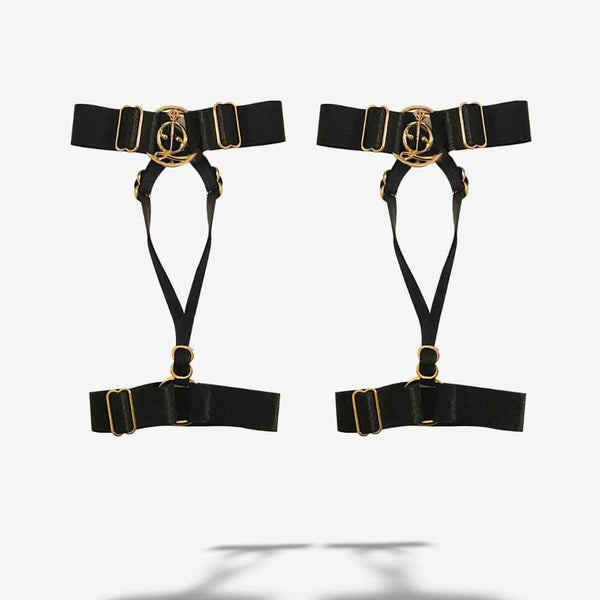 Harnais pour chevilles ajustables accessoire de lingerie réalisé en élastiques haut de gamme recyclés, doux mais résistants, ornés de composants en Zamac plaqué or 18 carats anti-rayures, lavables et hypoallergéniques ainsi que de l’anneau signature QRUCIFIX