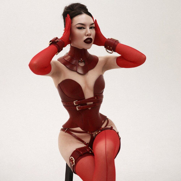Corset Daelos, string Astrea, contraintes de cuisse et menottes Magnus en cuir rouge pleine fleur avec finitions métalliques, créations bondage artisanales RE:STRICT.