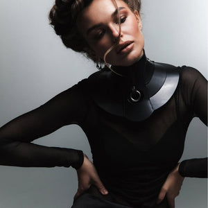 Mannequin portant le collier Posture Hold en cuir noir RE:STRICT chez Brigade Mondaine Paris, pièce rigide couvrant le cou, anneau métallique central, porté avec un top en mesh noir en studio.