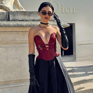Mannequin portant le corset Daelos en cuir rouge RE:STRICT chez Brigade Mondaine Paris, décolleté plongeant structuré, sangles ajustables, porté avec accessoires assortis sur fond rouge.