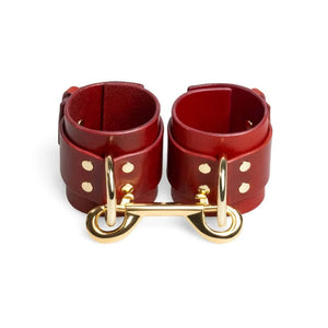 Menottes en cuir rouge ajustables avec D-ring et lien métallique doré création bondage minimaliste et artisanale signée RE:STRICT