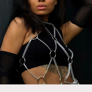 Harnais en chaînes argentées pour femme porté sur top noir, body harness tendance avec anneaux métalliques