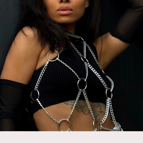 Harnais en chaînes argentées pour femme porté sur top noir, body harness tendance avec anneaux métalliques