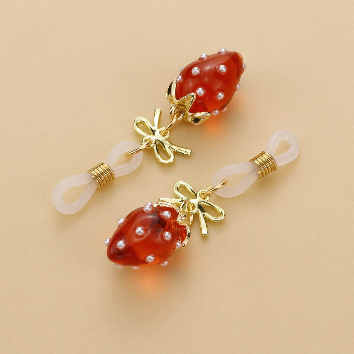 Pinces pour tétons Fraises de la marque Liebe Seele, ornées de breloques fraise rouges translucides et d’éléments dorés, présentées sur fond clair dans l’univers Brigade Mondaine Paris.