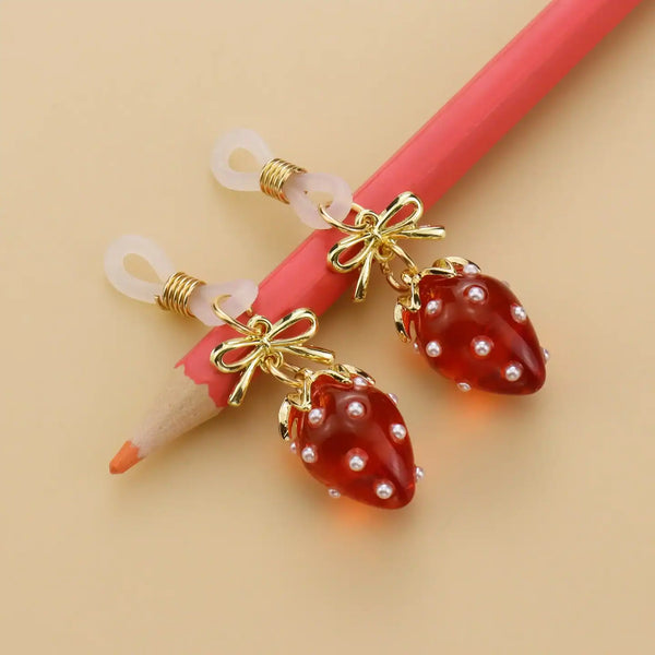Pinces pour tétons Fraises de la marque Liebe Seele, ornées de breloques fraise rouges translucides et d’éléments dorés, présentées sur fond clair dans l’univers Brigade Mondaine Paris.
