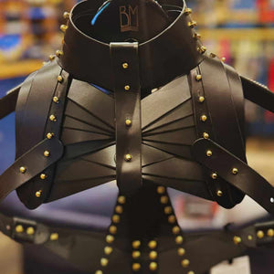 Holster d’épaule en cuir noir signé Úna Burke, inspiré des étuis pour armes à feu, avec raccords en laiton massif recouverts d’or et vis en laiton, créant une pièce rock chic et structurée, portée par des icônes comme Janet Jackson et Rihanna.