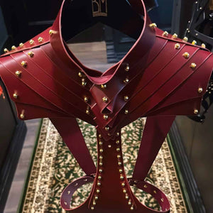 Attelle corporelle en cuir bordeaux d'Úna Burke avec raccords en laiton doré et vis en laiton, un harnais sculptural et polyvalent, à porter sur chemise ou peau nue pour une touche audacieuse.