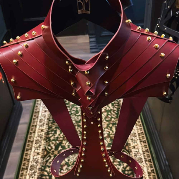 Attelle corporelle en cuir bordeaux d'Úna Burke avec raccords en laiton doré et vis en laiton, un harnais sculptural et polyvalent, à porter sur chemise ou peau nue pour une touche audacieuse.