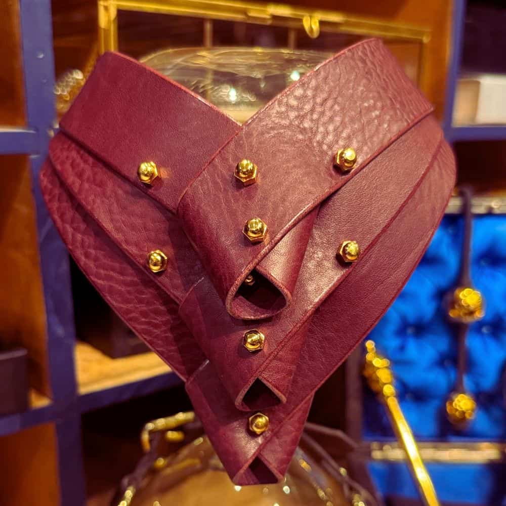 Collier Turned en cuir merlot d'Úna Burke, avec panneaux pliés et bandes de cuir tanné végétal, alliant chic et bondage pour une touche avant-gardiste et féminine.