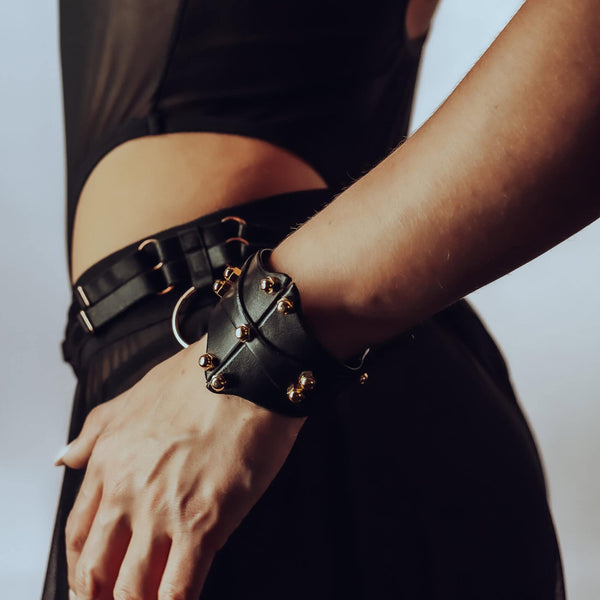 Bracelet de type manchette signée Una Burke en cuir noir de vache tanné végétal les raccords en laiton massif recouverts d’or et les vis en laiton.