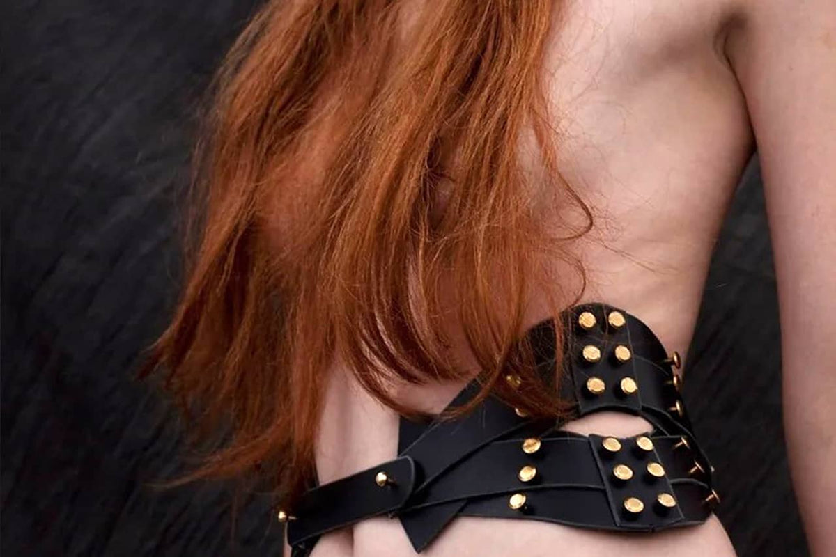Harnais shoulder holster d'épaule en cuir noir de Una Burke porté par une femme nue sur un fond noir.