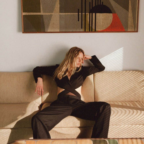 Photo d'une Femme Assise de Devant portant un Body Blazer avec résille et Croisé avec un Pantalon couleur Noir