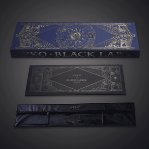 Photographie sur fond gris du packaging bleu et doré, boite avec pochon en velour écris “UPKO BLACK LABEL COLLECTION"