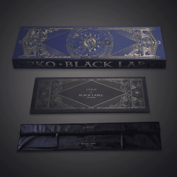 Photographie sur fond gris du packaging bleu et doré, boite avec pochon en velour écris “UPKO BLACK LABEL COLLECTION"