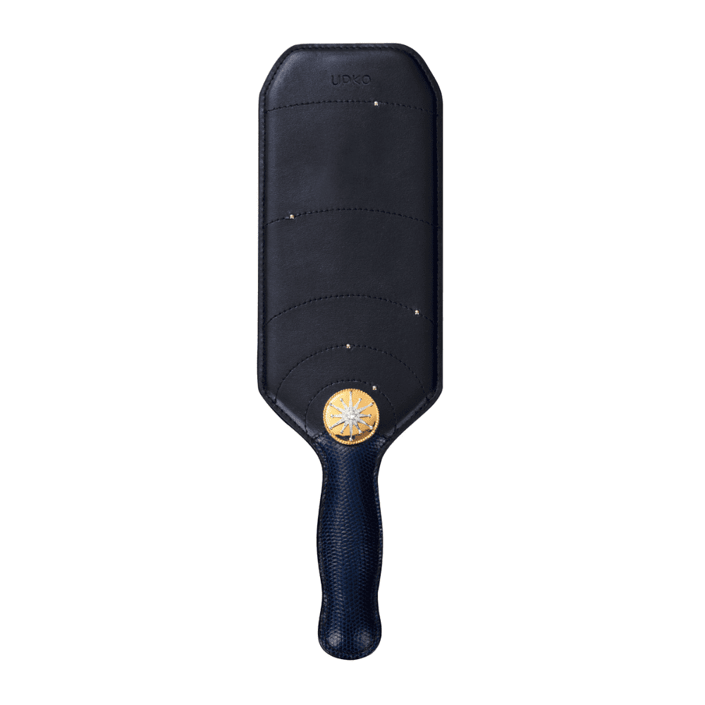 Packshot du paddle de cuir noir avec manche en peau de lézard avec détails en or.