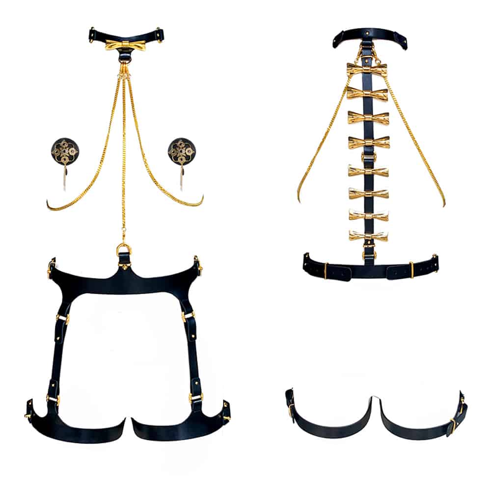 Ensemble Bondage 8 pièces de la marque Upko noir et or. Se trouve au niveau du cou un collier qui est relié à la ceinture par une chaîne en or. De part et d’autre, se trouvent des chaines couleur or qui relient le haut et le bas en diagonale. Les chaînes sont reliées à des nippies noir avec des motifs or. À l’arrière des noeuds couleur or qui descendent le long du dos. De part et d’autre, se trouvent des chaines couleur or qui relient le haut et le bas du harnais en diagonale.Le bas est noir et le haut des 