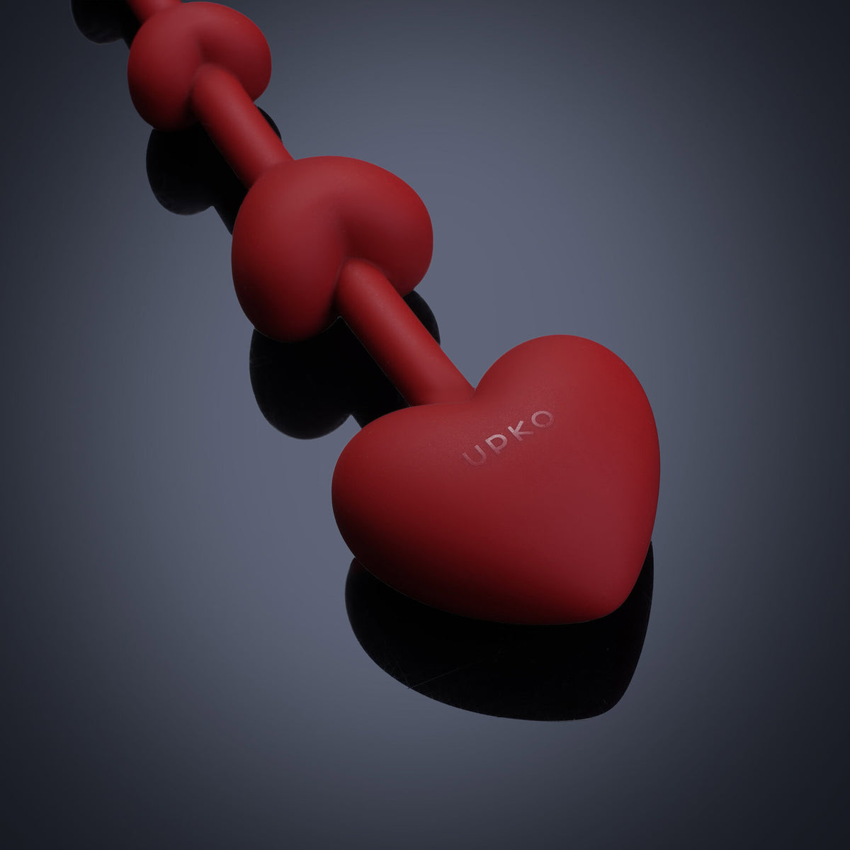 Accessoire anal UPKO en silicone rouge en forme de cœurs sur fond sombre Brigade Mondaine Paris