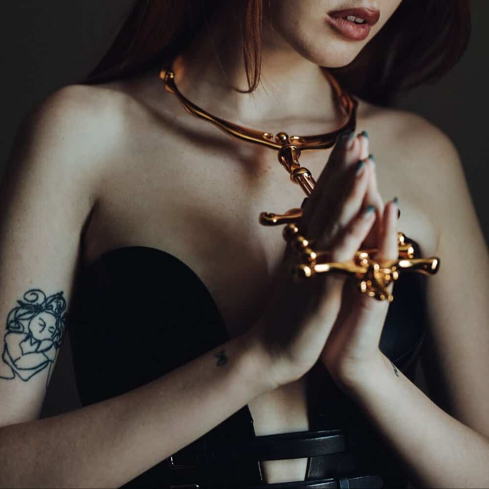 Collier et menottes BDSM UPKO en métal doré portés ensemble dans une mise en scène éditoriale Brigade Mondaine Paris