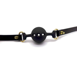Baillon en cuir noir et silicone en forme de boule avec trous pour respiration, finition or UPKO chez Brigade Mondaine