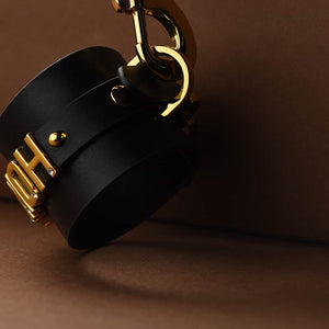 Vue rapprochée d'une menotte en cuir noir italien avec des accroches en or plaqué 24 carats et gravés par la marque UPKO pour l'édition limitée UPKO X Brigade Mondaine chez Brigade Mondaine