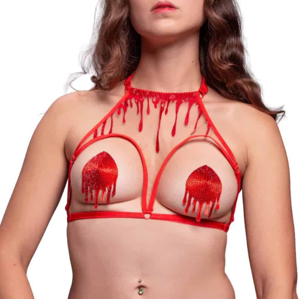 Mannequin portant les cache-tétons Blood rouges VIDE NOIR chez Brigade Mondaine Paris, motifs brodés en forme de gouttes, portés avec un ensemble rouge assorti, photographié en studio.