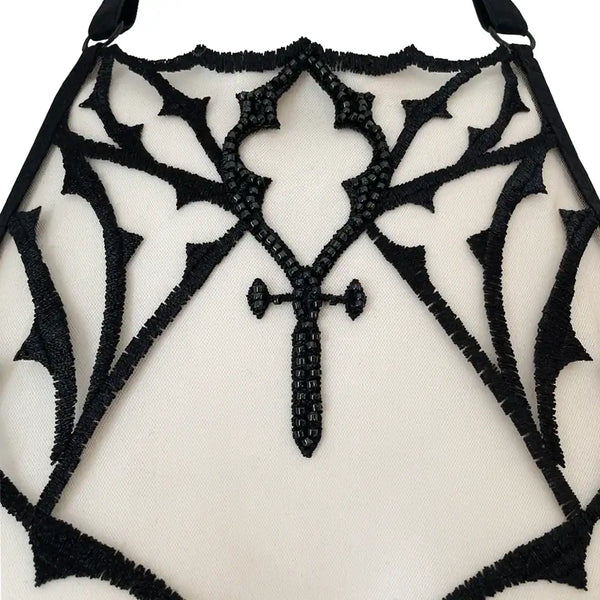 Soutien-gorge gothique en tulle nude brodé noir avec perles facettées. Demi-bonnets en satin noir doublé et col licou réglable. Élégance dramatique et maintien confortable.