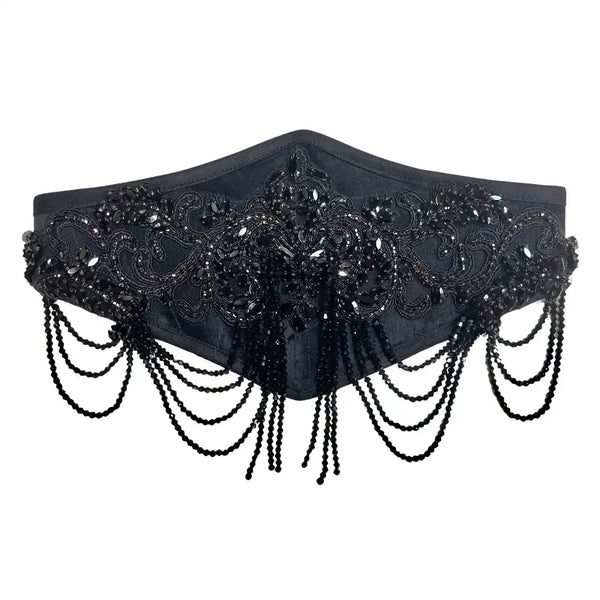 Handmade black velvet waist belt featuring an intricate hand-applied glass-beaded appliqué and cascading rows of faceted black glass beads. Designed to combine structure and fluid movement, this belt is crafted on a soft velvet base and finished with an adjustable velvet elastic band for comfort, flexibility, and a secure fit on the waist or hips. Each piece is meticulously crafted upon order, making every creation unique. For this reason, bead placements and appliqué details may vary slightly from those pi