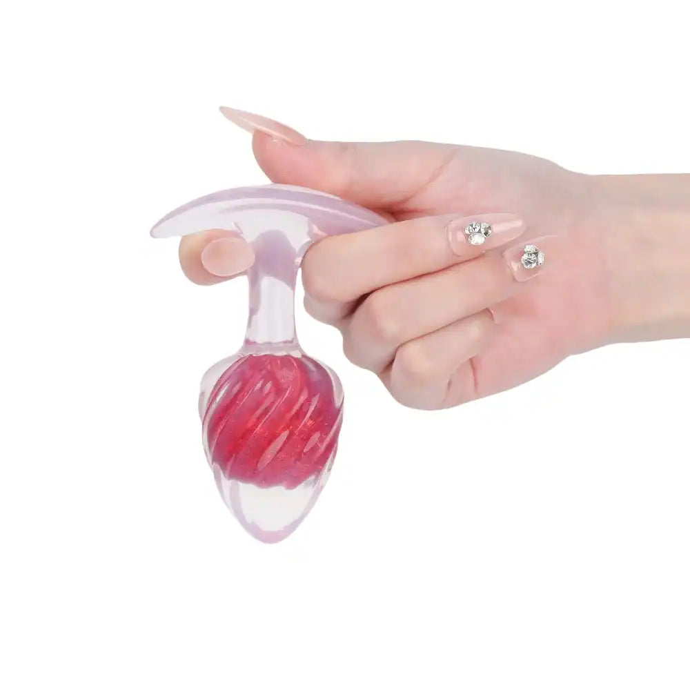 Plug en silicone rouge LIEBE SEELE avec surface spiralée et base transparente évasée, tenu en main sur fond blanc, vue produit détaillée