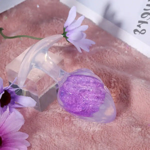 Plug en silicone violet LIEBE SEELE avec surface spiralée et base transparente évasée, tenu en main sur fond blanc, vue produit détaillée