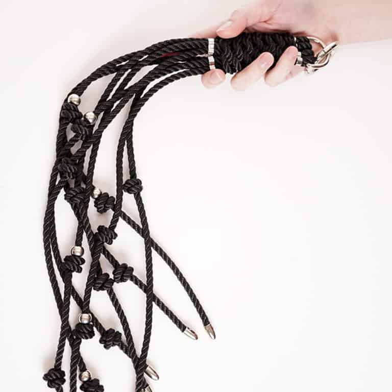 Peitsche aus schwarzen Seilen mit kleinen Knoten und silbernen Details für mehr Gefühl