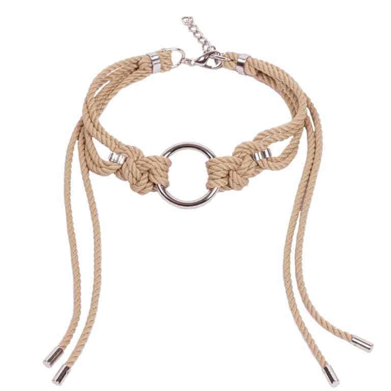 Ce Choker Shippo Beige élaboré et ajusté comprend un grand joint torique avec des nœuds traditionnels symétriques en corde de polyester, avec de longues queues lâches encadrant le cou. Il est fini avec un alliage de zinc argenté et une quincaillerie en laiton. Un fermoir et une chaîne à l’arrière peuvent être ajustés pour un ajustement personnalisé. Taille unique. Disponible chez Brigade Mondaine.