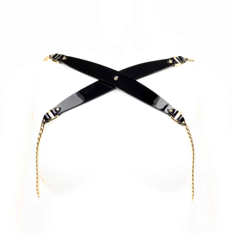 Chic et sexy! Notre harnais Rica Chain est fabriqué à la main à partir de cuir verni noir, fini avec des rivets et une chaîne en laiton plaqué or 24K de haute qualité, et des fermetures élastiques satinées réglables pour envelopper confortablement votre corps. Portez ce harnais glamour sur votre blouse en soie préférée, robe ou directement contre la peau. Bracelets en cuir verni noir Rivets et chaîne à double capuchon en laiton plaqué or 24 carats Sangles élastiques en satin à double face noire ajustable Crochet arrière extensible réglable Disponible en deux tailles - un (S/M) et deux (M/L). Veuillez consulter le tableau des tailles pour les mesures.