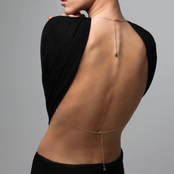 Photo of a Woman from the Back wearing a Gold Bust Jewel with Swarovski jewels and Cross with a Black Outfit