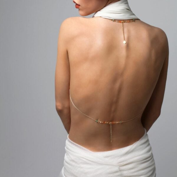 Photo of a Woman from the Back wearing a Golden Bust Jewel with Swarovski and Jade Jewelry with a White Outfit