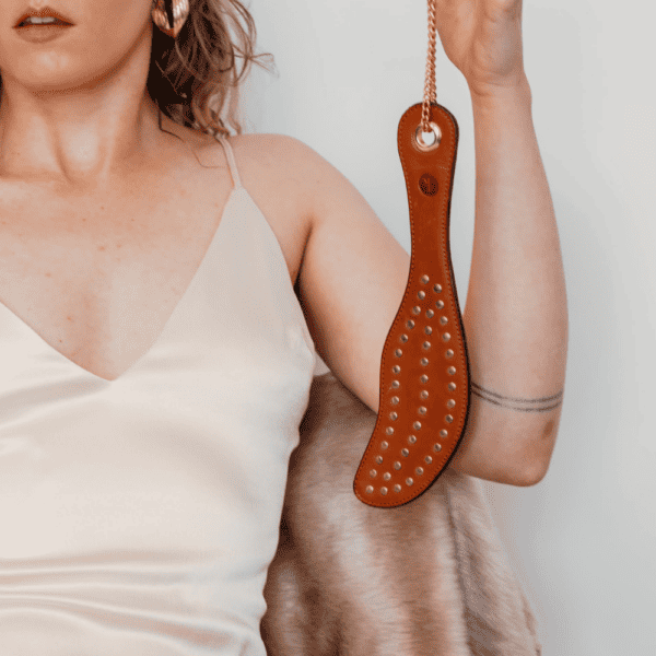Photo of a tan leather studded paddle.