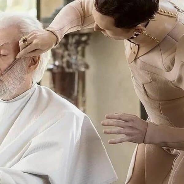 Woman styling a man's beard while wearing a beige leather Una Burke top.