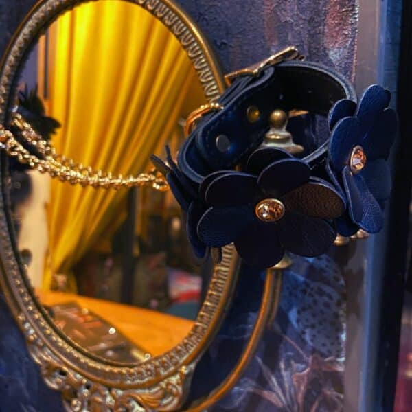 Halskette und Leine aus Leder im Blumendesign, die auf einem Spiegel an einer Wand liegen.