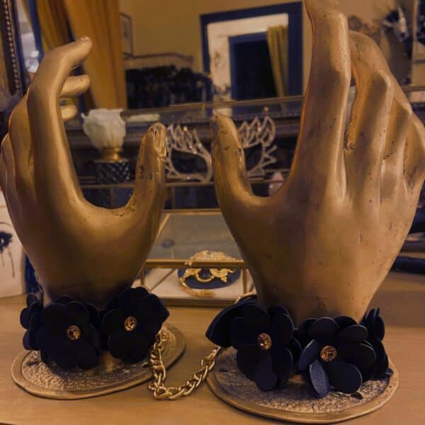 Handschellen aus schwarzem Leder im Blumendesign, die von falschen Händen getragen werden.