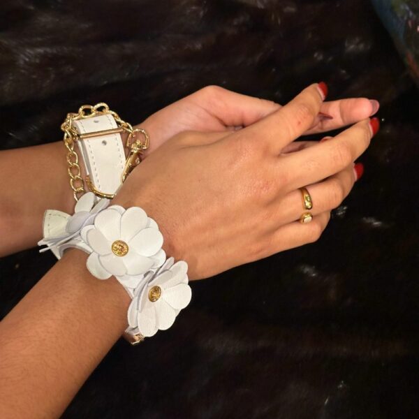 Bild von Handschellen aus weißem Leder mit weißen Lederblumen und goldener Kette mit schwarzem Pelzhintergrund