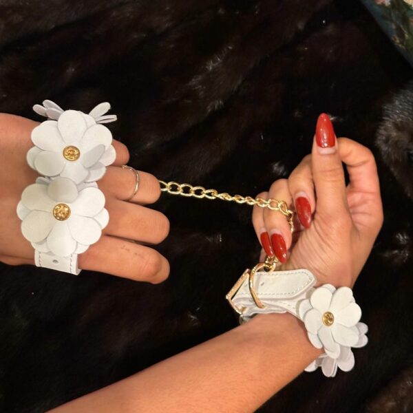 Image of White Leather Handcuffs with White Leather Flowers and Gold Chain with Black Fur Background