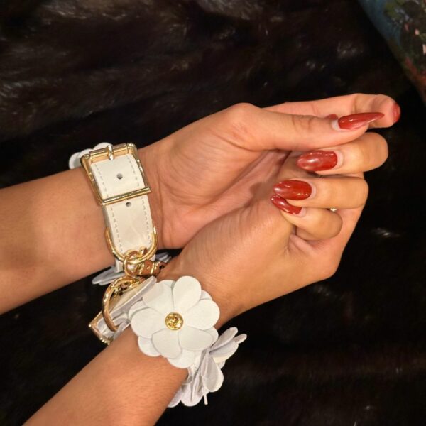 Image of White Leather Handcuffs with White Leather Flowers and Gold Chain with Black Fur Background