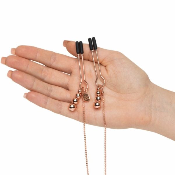 Hand holding Nipple Clamps from the Pink Gold Nipple and Clitoris Clamp Packshot