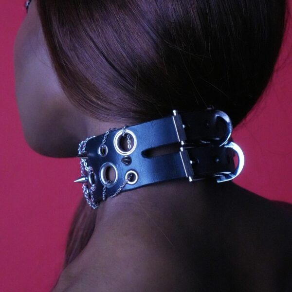 Femme de 3/4 Dos portant un Choker en Cuir Noir avec Anneaux, Chaînes et Rivets Argents