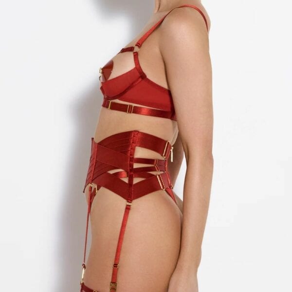 Femme portant un ensemble de lingerie rouge en satin, avec un porte-jarretelles structuré et des détails dorés, vue de profil.